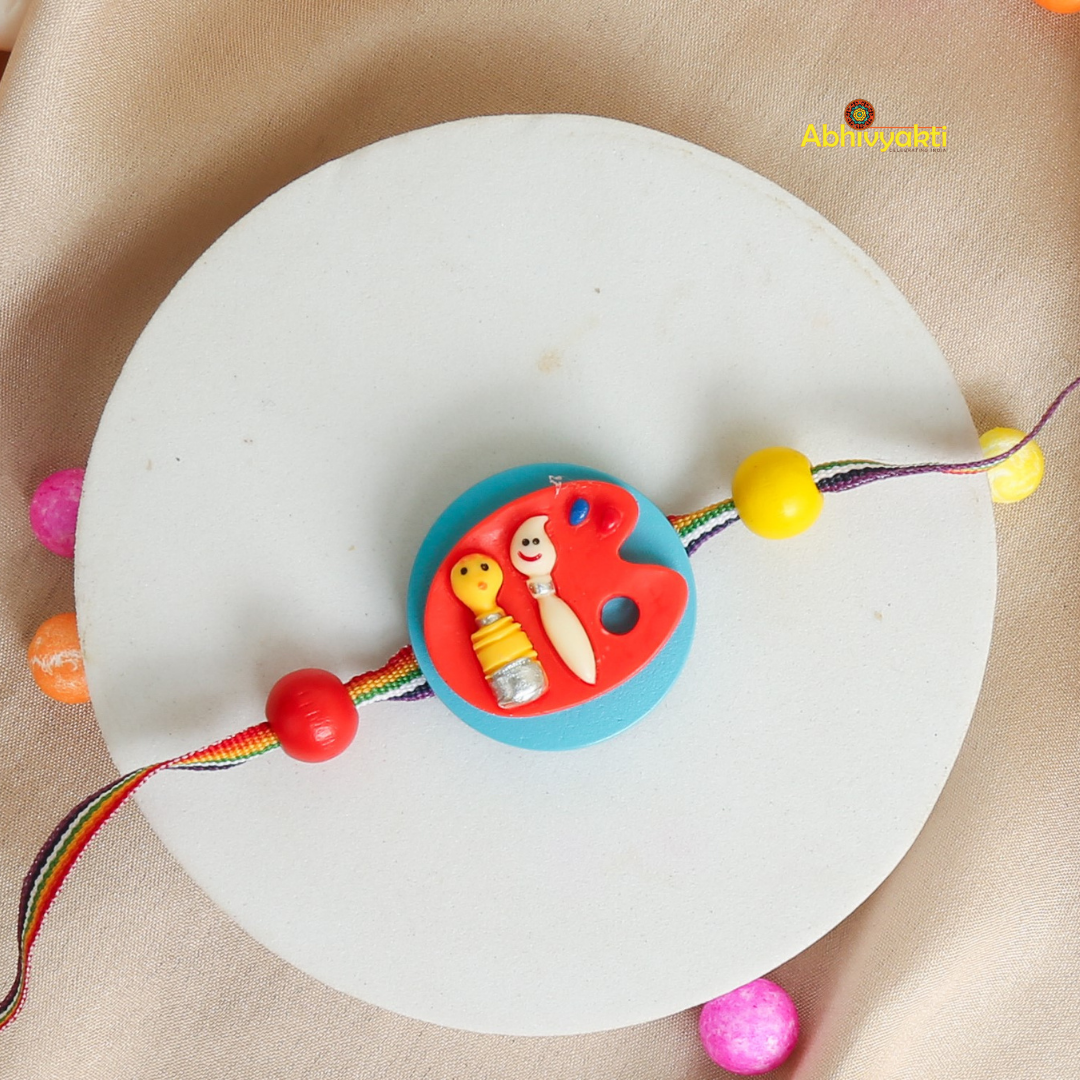 A colorful rakhi with a blue and red circular centerpiece featuring, smiling baby face, on a multicolored thread with beads, displayed on a white round base.