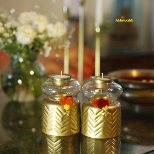 Anuya Tealight Holder Pair with flowers on a reflective surface, blurred background