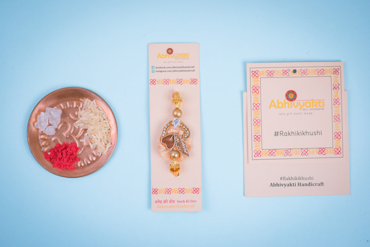 Beautiful golden copper zari rakhi with a festive greeting card and roli rice plate to celebrate Rakshabandhan