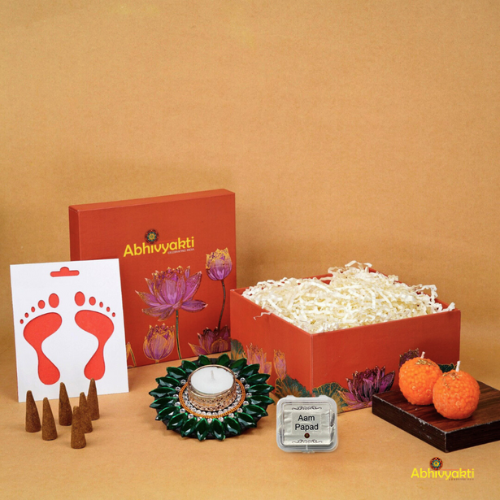 A festive Diwali hamper filled with an assortment of decorative items and treats. The hamper includes colorful floating diya, a box of mithai sweet candle, fragrant incense sticks, a small decorative toran, and festive Ganesh Lakshmi tealight alongwith tangy juicy mango roll up . The items are beautifully arranged in a festive box with vibrant, rich colors and intricate detailing, evoking the spirit of Diwali celebrations. The hamper is a perfect gift for the festive vibe