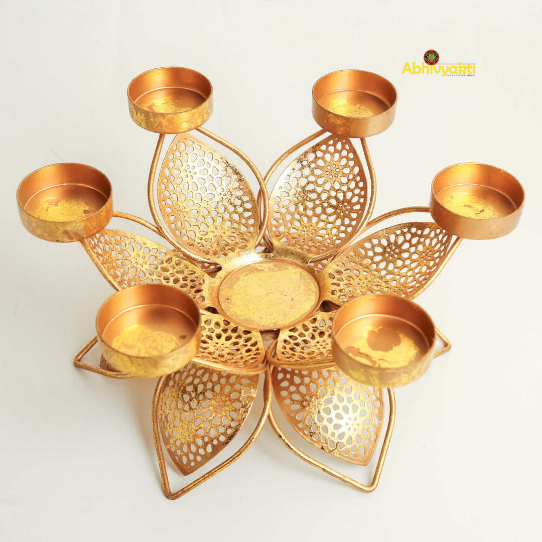 Golden metal padam t-light holder in a flower shape with six intricate perforated petals, each petal holding a small round cup for candles, placed on a white background