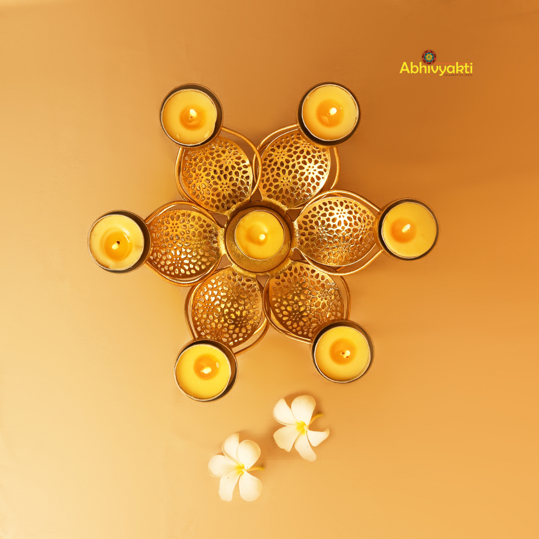 Golden metal padam t-light holder in a flower shape with six intricate perforated petals, each petal holding a small round cup for candles, placed on a yellow background