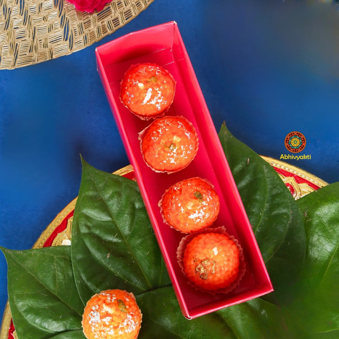Decorative, usable soy wax candles shaped like traditional Indian sweets (motichoor ladoos), adorned with silver foil detailing, placed in festive packaging. Perfect for gifting and festive home decor
