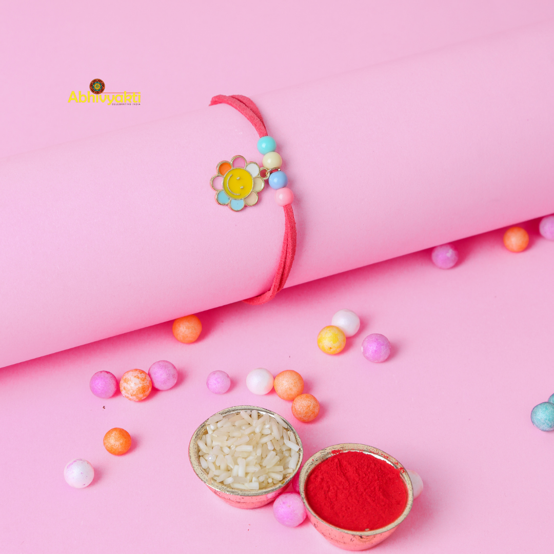 Cute and colorful Rainbow kids' bracelet featuring a red suede strap, pastel beads, and a cheerful multicolored flower charm with a smiling face, displayed on a pink background