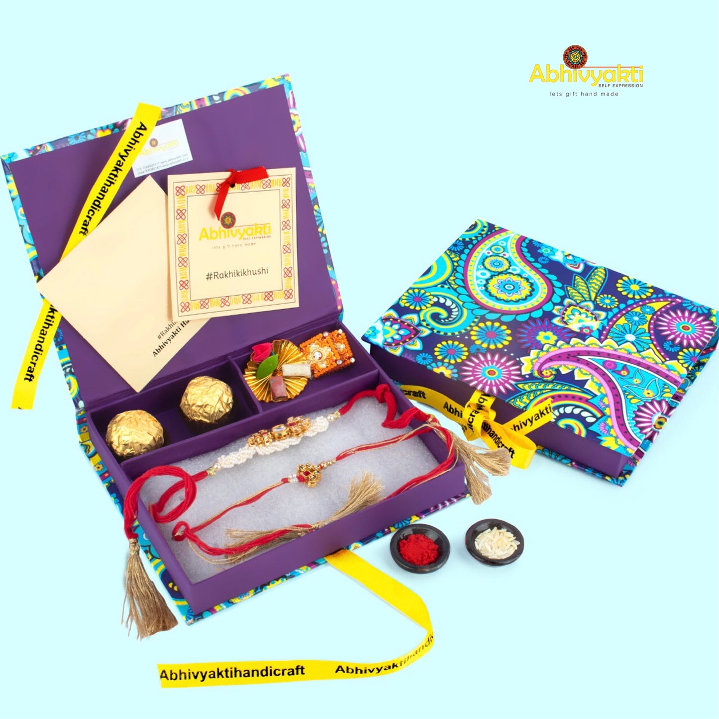 Elegant lumba rakhi set with red threads, golden tassels, and intricate kundan designs, displayed on a maroon background with scattered rice, roli, chocolates.