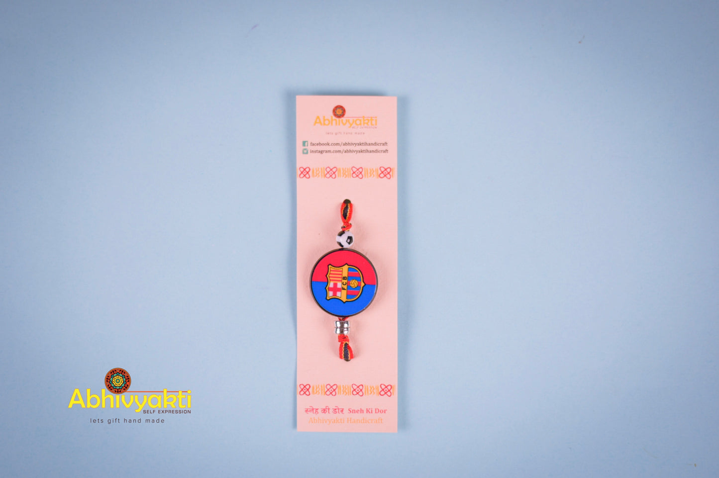 FC Barcelona themed Rakhi featuring the FCB logo on a round dial with a football bead and multicolored band perfect for young football fans.