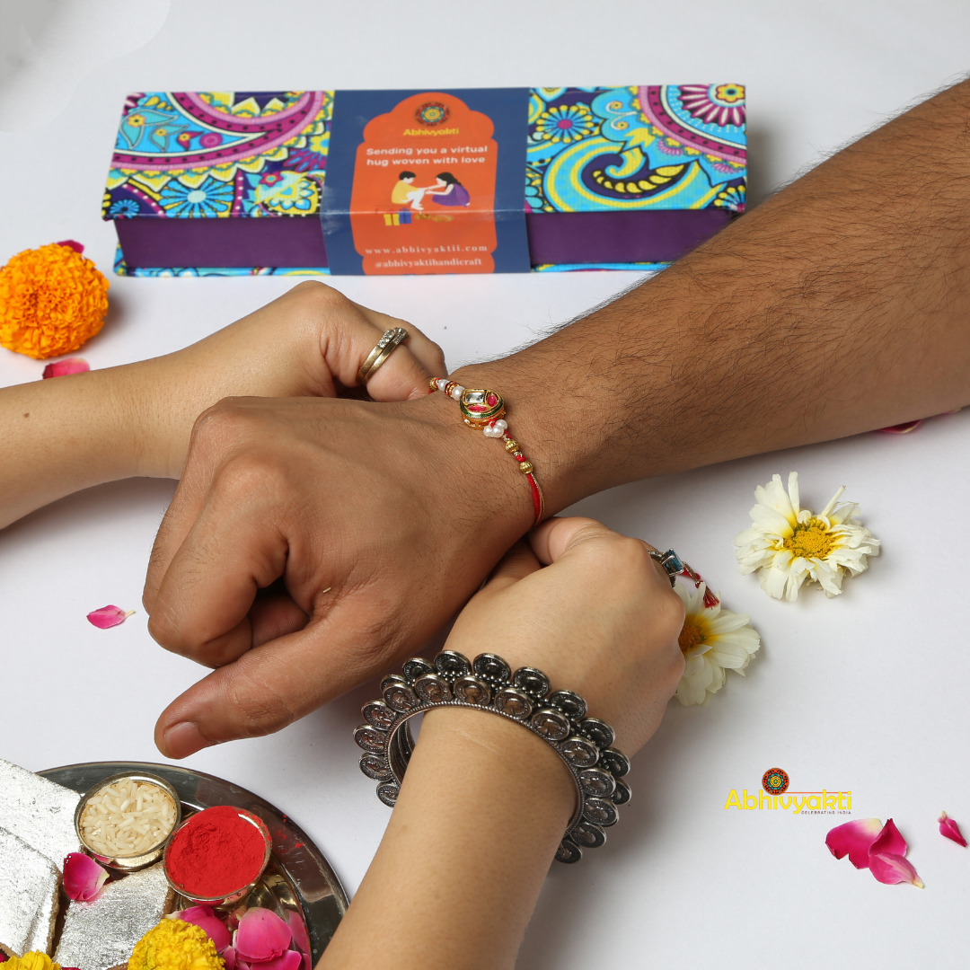Kundan rakhi with red and green colors, adorned with gold and green stone and lovely beads.