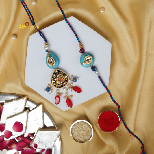 Blue and red Rakhi and lumba featuring a turquoise stone and intricate design.