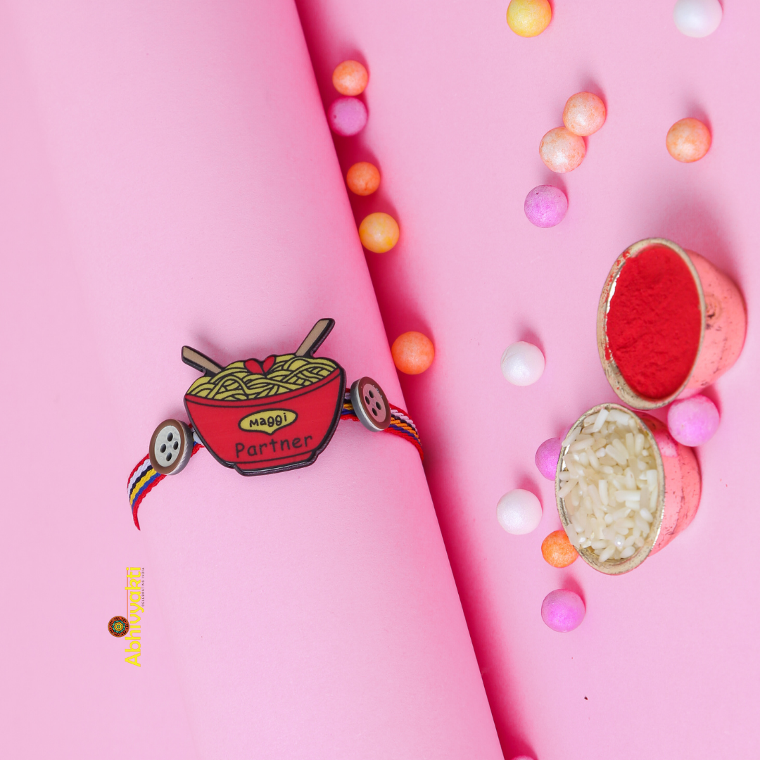 Kids rakhi in red and yellow with beads, noodles, and a button.