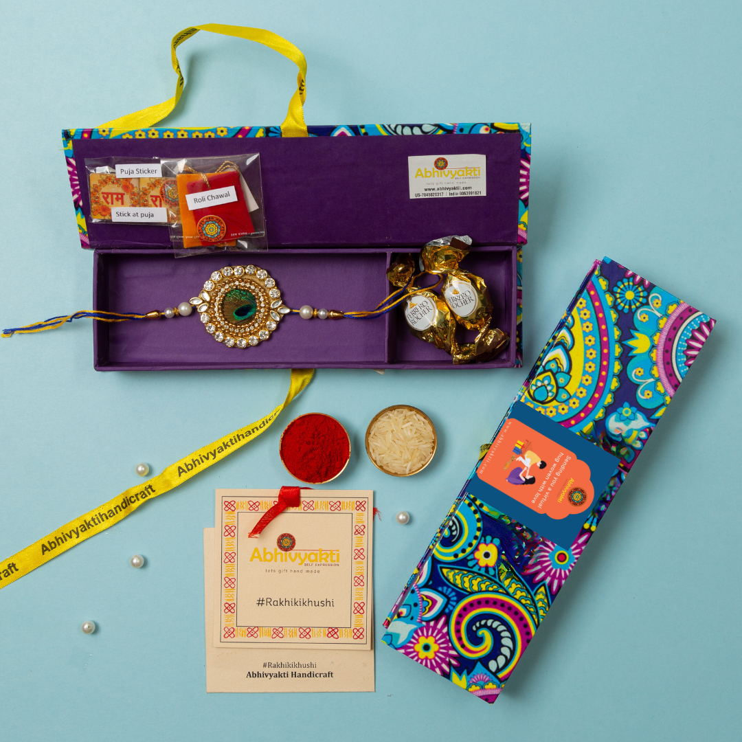 A colorful peacock feather centre rakhi with a gold and blue bead, packed in a beautiful hamper premium quality box