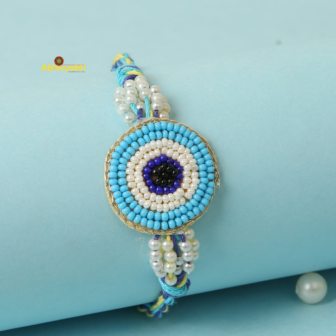 Stunning rakhi adorned with Sky blue and white beads and a blue eye charm.