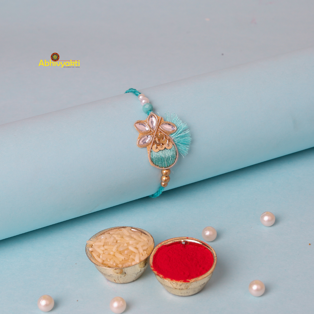 A delicate turquoise and gold stone rakhi with stone embellishments