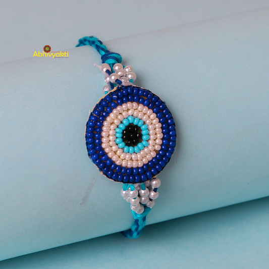 Stunning rakhi adorned with blue and white beads and a blue eye charm.