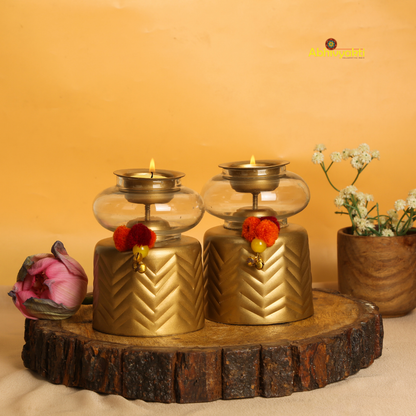 Anuya Tealight Holder Pair with flowers on a reflective surface, yellow background