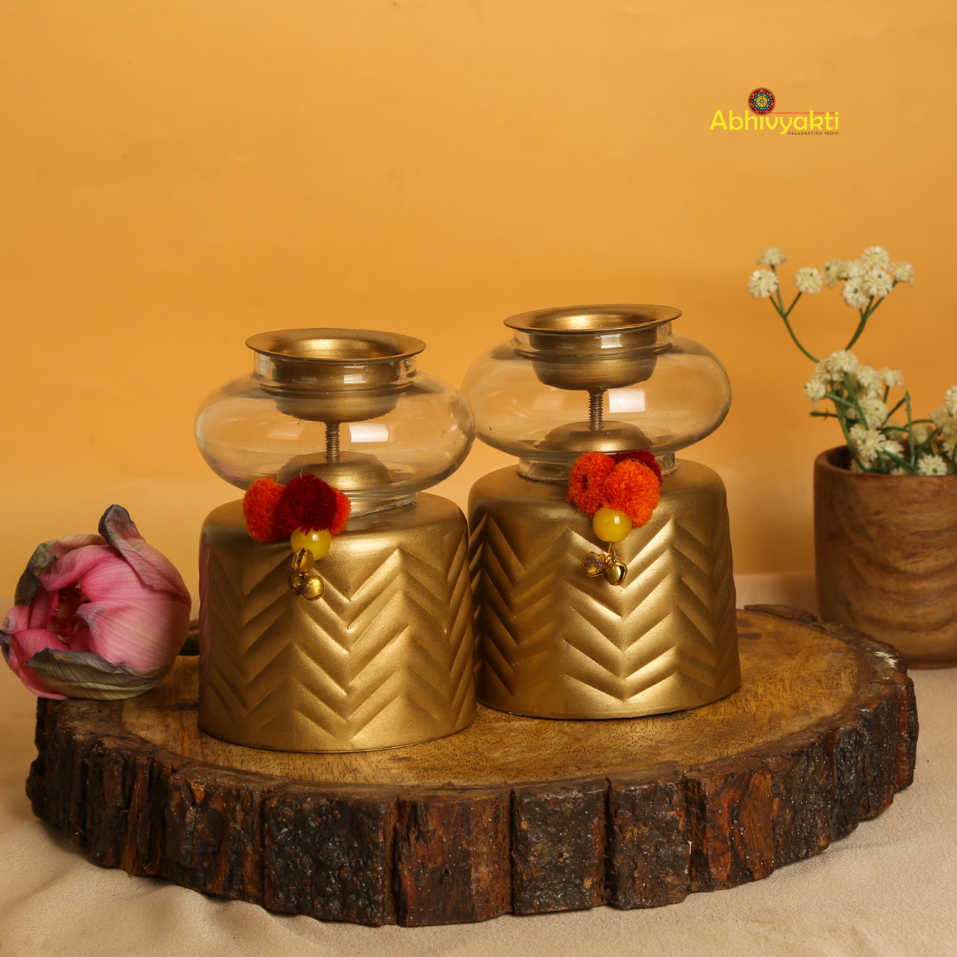 Anuya Tealight Holder Pair with flowers on a reflective surface, yellow background