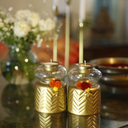 Anuya Tealight Holder Pair with flowers on a reflective surface, blurred background