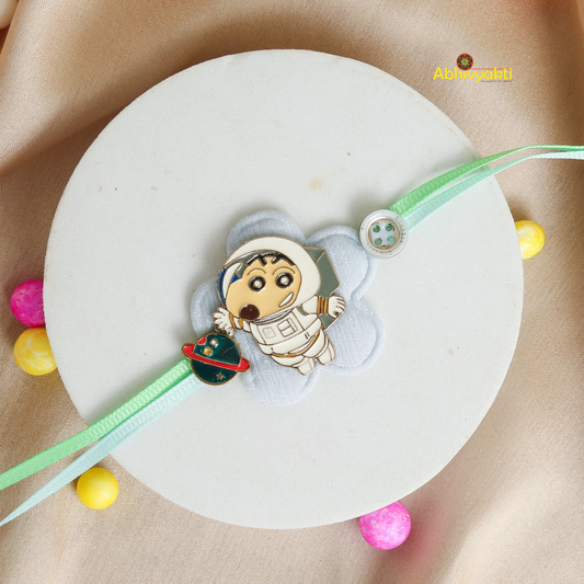 Vibrant Baby Astronaut Rakhi bracelet for kids, featuring a cute cartoon astronaut and spaceship charm on a pastel green thread, displayed on a soft beige background with colorful decorative balls.