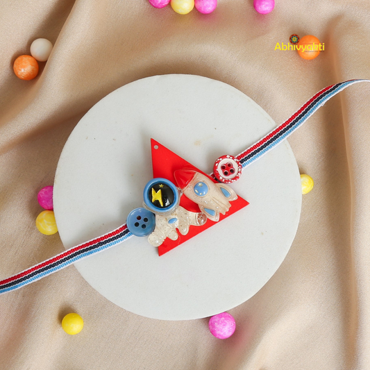 Baby Astronaut Rakhi bracelet for kids, with a cute cartoon astronaut and spaceship charm on a pastel green thread, placed on a beige background with colorful balls around it.