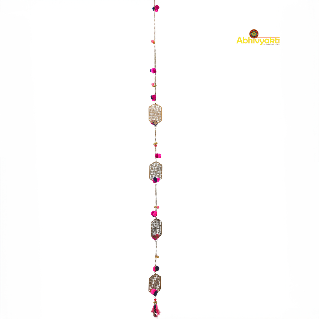 Filigree designed metallic door hanging with red and purple pom-poms, suspended against a white background