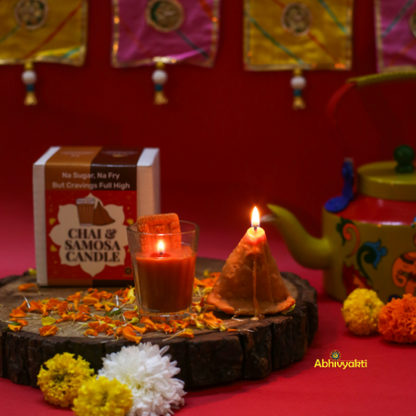 Decorative, usable soy candles shaped like a glass of chai with a biscuit and a triangular samosa, designed to look like popular Indian snacks