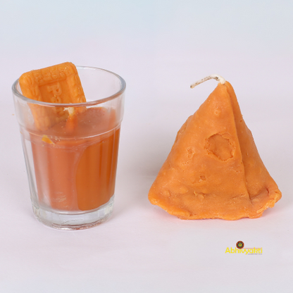 Decorative, usable soy candles shaped like a glass of chai with a biscuit and a triangular samosa, designed to look like popular Indian snacks