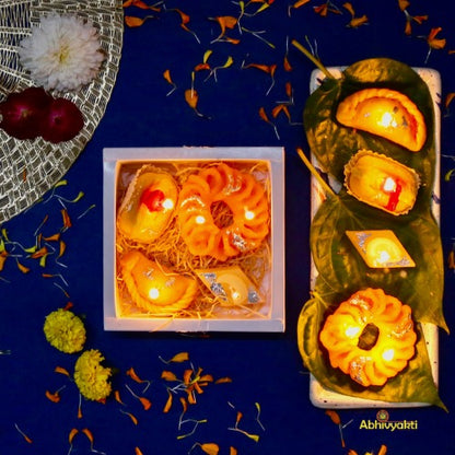 Decorative, usable soy wax candles designed to resemble traditional Indian sweets like gujiya, peda, imarti, and barfi, beautifully arranged in a pastel green gift box with a transparent window.  ideal for gifting during Indian festival