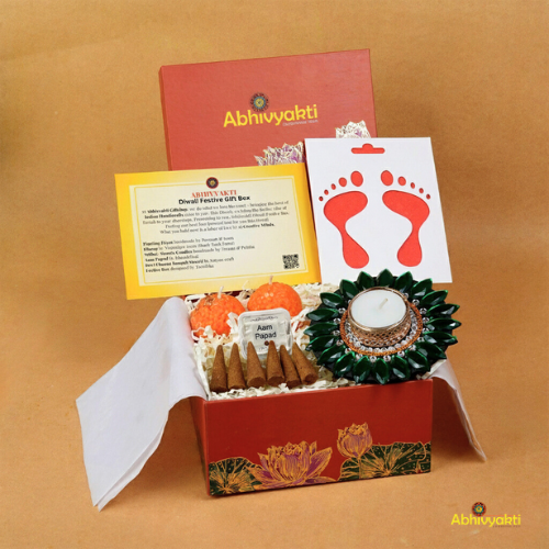 A festive Diwali hamper filled with an assortment of decorative items and treats. The hamper includes colorful floating diya, a box of mithai sweet candle, fragrant incense sticks, a small decorative toran, and festive Ganesh Lakshmi tealight alongwith tangy juicy mango roll up . The items are beautifully arranged in a festive box with vibrant, rich colors and intricate detailing, evoking the spirit of Diwali celebrations. The hamper is a perfect gift for the festive vibe