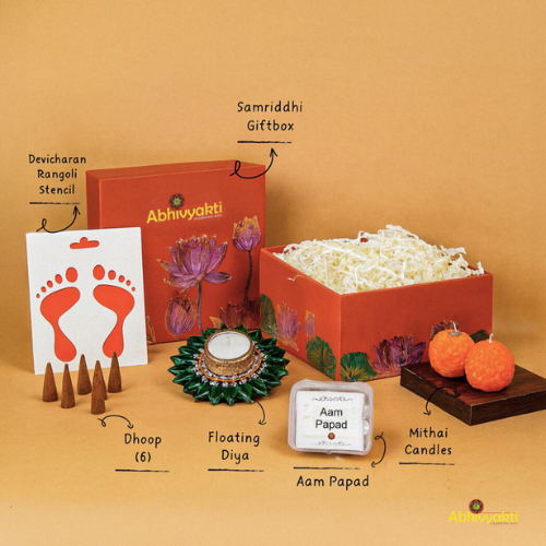 A festive Diwali hamper filled with an assortment of decorative items and treats. The hamper includes colorful floating diya, a box of mithai sweet candle, fragrant incense sticks, a small decorative toran, and festive Ganesh Lakshmi tealight alongwith tangy juicy mango roll up . The items are beautifully arranged in a festive box with vibrant, rich colors and intricate detailing, evoking the spirit of Diwali celebrations. The hamper is a perfect gift for the festive vibe
