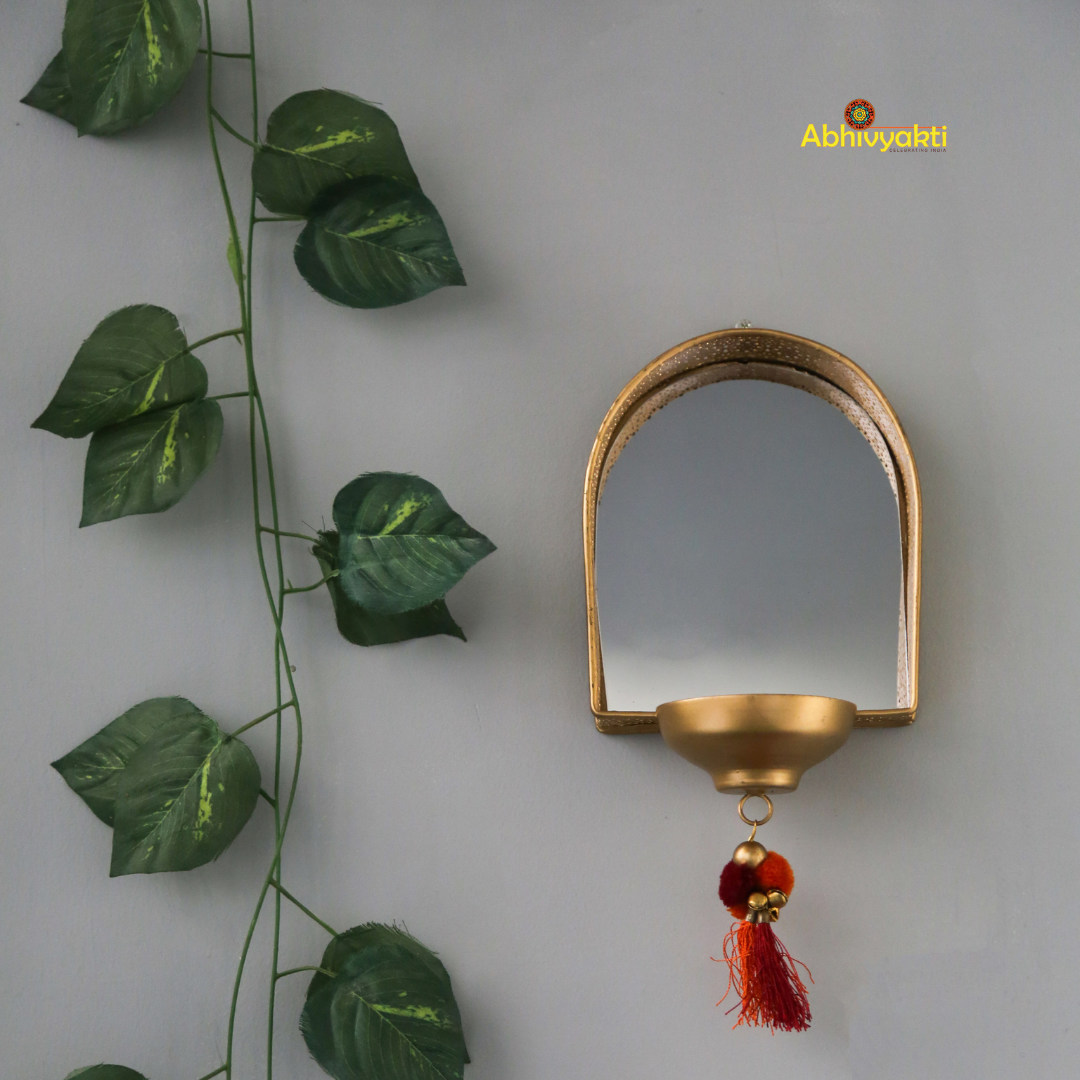 Decorative mirror tealight holder for Diwali decor with leaf garlands on a plain background