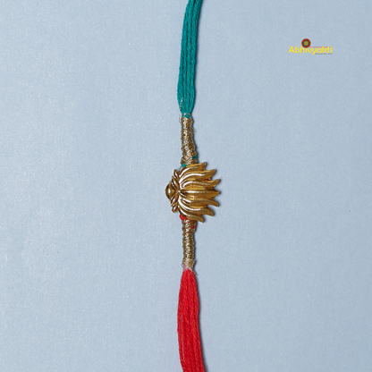 Elegant Rakhi featuring a golden lotus charm at the center, tied with contrasting red and teal threads. A minimal yet traditional design, perfect for celebrating Raksha Bandhan with a touch of symbolism and style