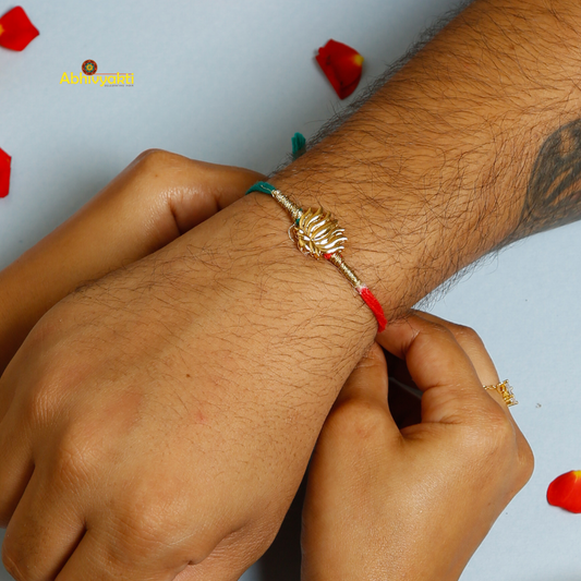 Elegant Rakhi featuring a golden lotus charm at the center, tied with contrasting red and teal threads. A minimal yet traditional design, perfect for celebrating Raksha Bandhan with a touch of symbolism and style