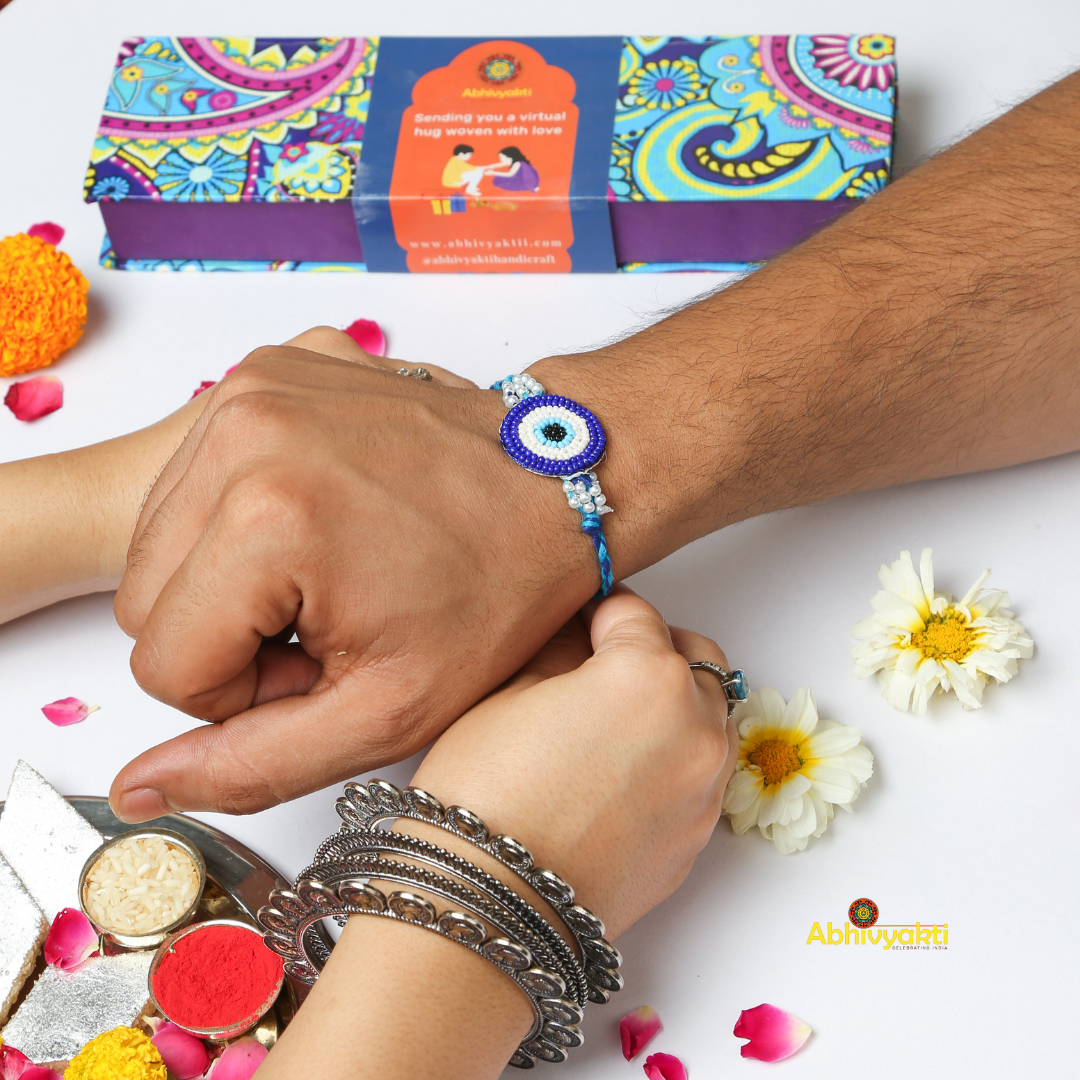 Handcrafted evil eye rakhi featuring blue, white, and turquoise seed beads on a braided blue thread, perfect for Raksha Bandhan gifting