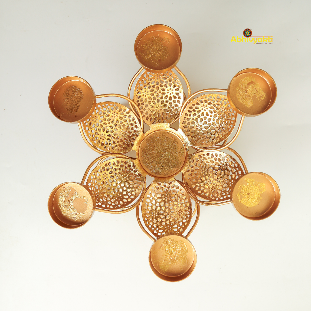 Golden metal padam t-light holder in a flower shape with six intricate perforated petals, each petal holding a small round cup for candles, placed on a white background