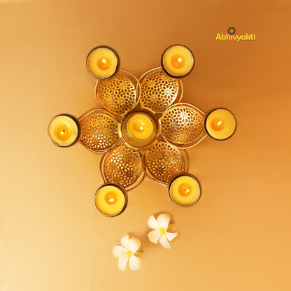 Golden metal padam t-light holder in a flower shape with six intricate perforated petals, each petal holding a small round cup for candles, placed on a yellow background