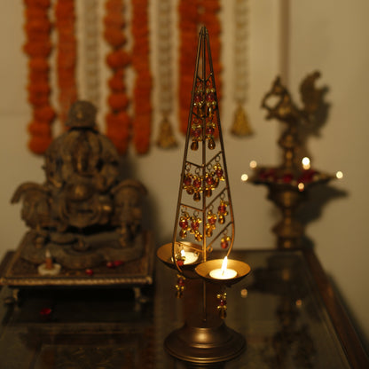 Decorative Kalp Taru tealight holder gold lamp with intricate design on a reflective surface.