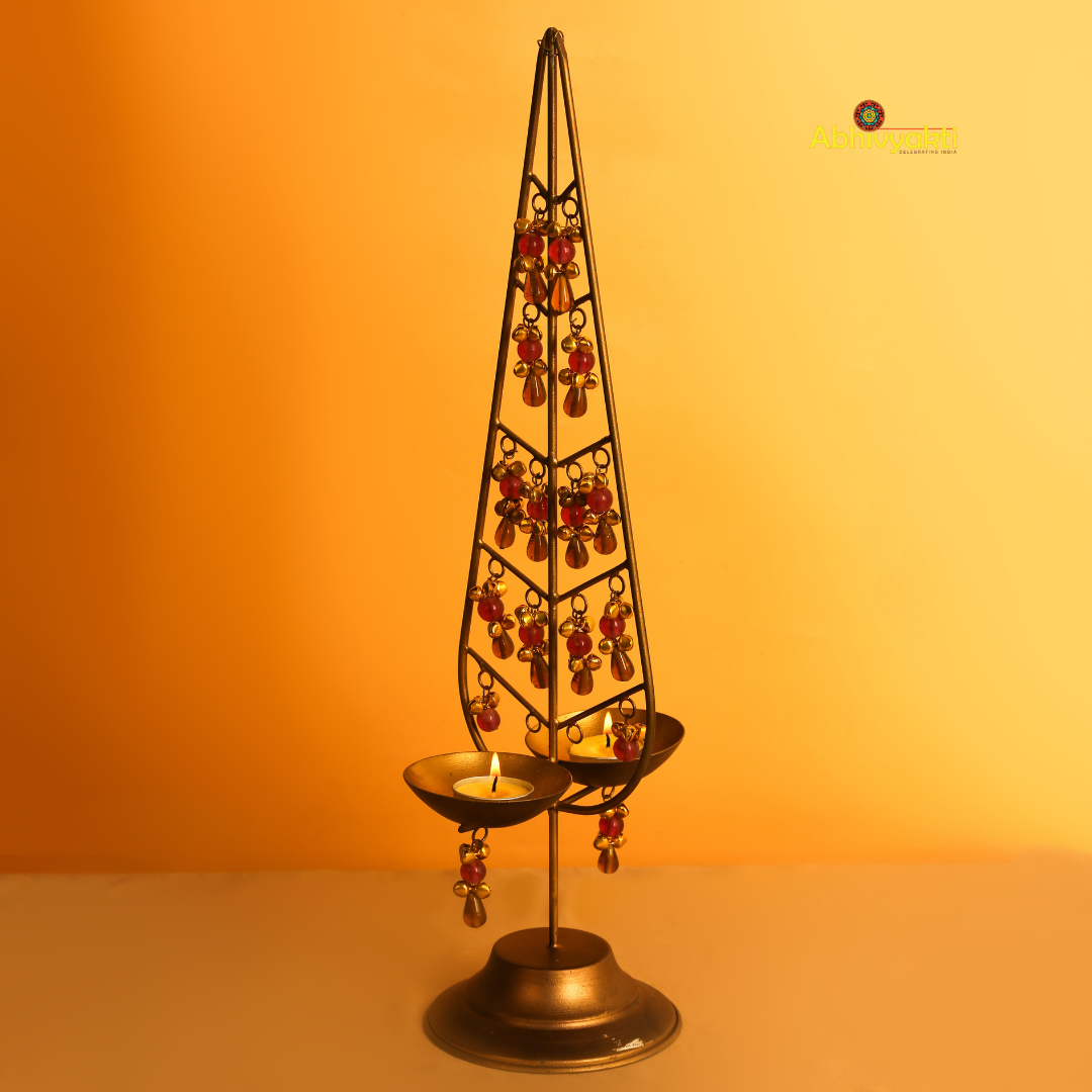 Kalp Taru table lamp with a triangular base and hanging red crystals, set against an orange background.