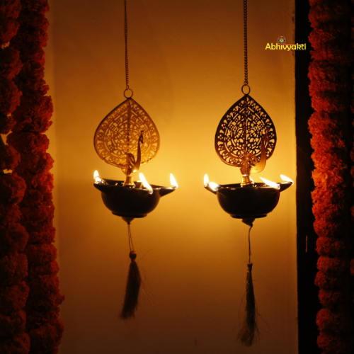 Decorative Peacock Swagata long chain T-light holder oil lamps with floral garlands on a warm-toned background