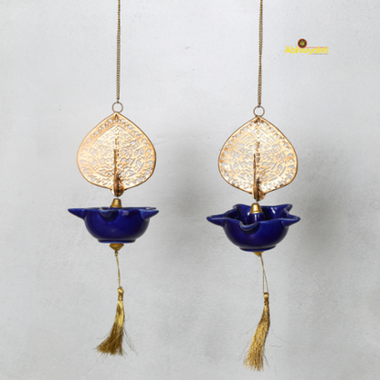 Two hanging decorative Peacock Swagata with blue bowls and gold leaf designs on a light gray background