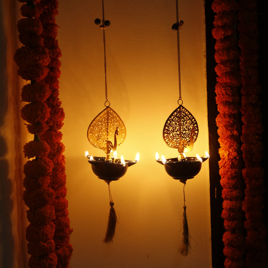 Decorative Peacock Swagata long chain T-light holder with lights against a sunset background