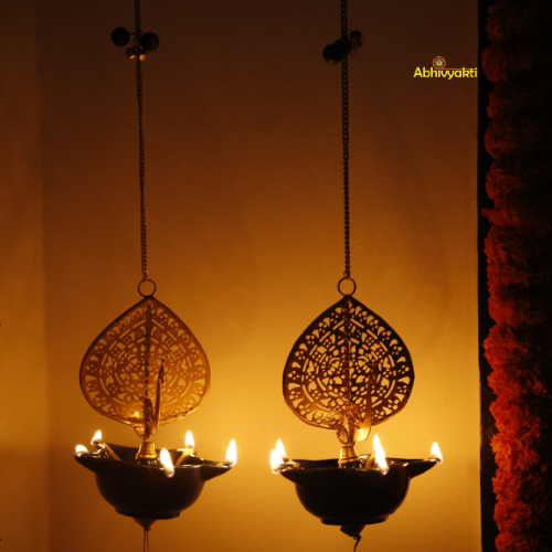 Decorative Peacock Swagata long chain T-light holder with intricate designs reflected on a surface, against a warm background.