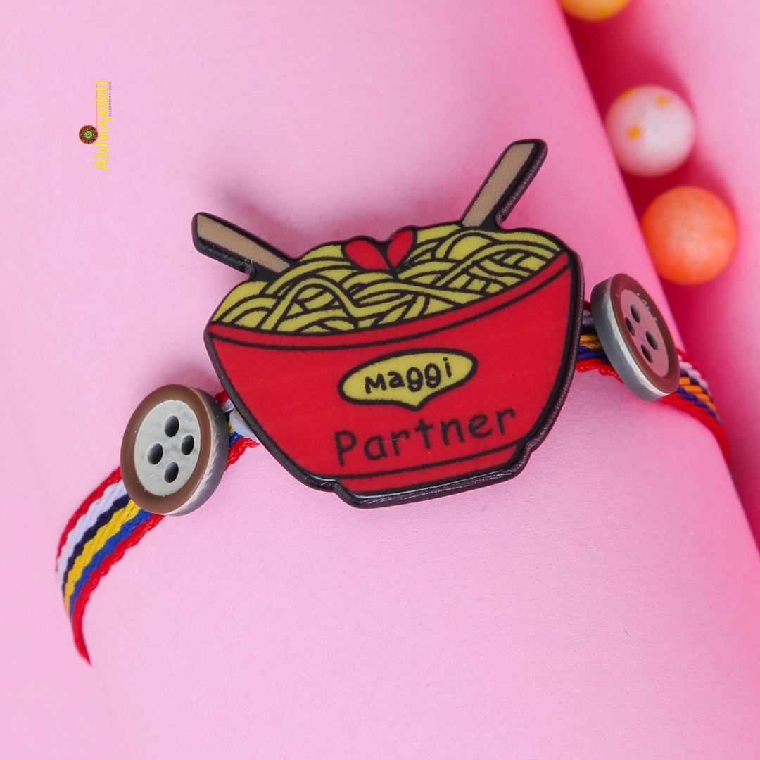Quirky Rakhi featuring a red bowl of noodles with “Maggi Partner” text, paired with multicolored thread and cute button accents — perfect for celebrating sibling bonds with a fun, foodie twist.