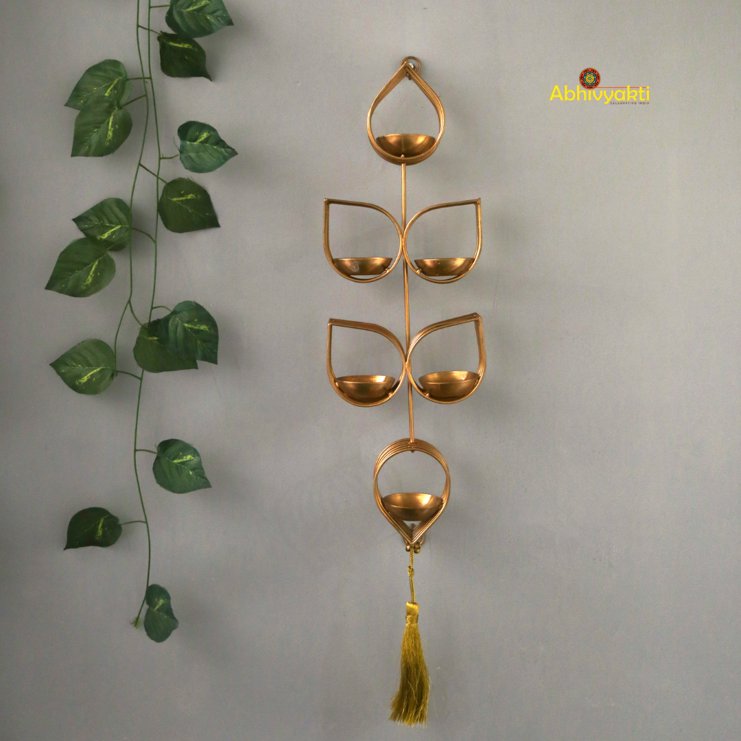 Tulsi - Wall Hanging Tealight Holder and orange beaded floral toran on a beige, gray background