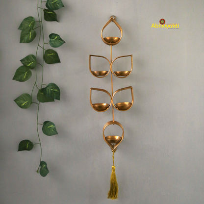 Tulsi - Wall Hanging Tealight Holder and orange beaded floral toran on a beige, gray background