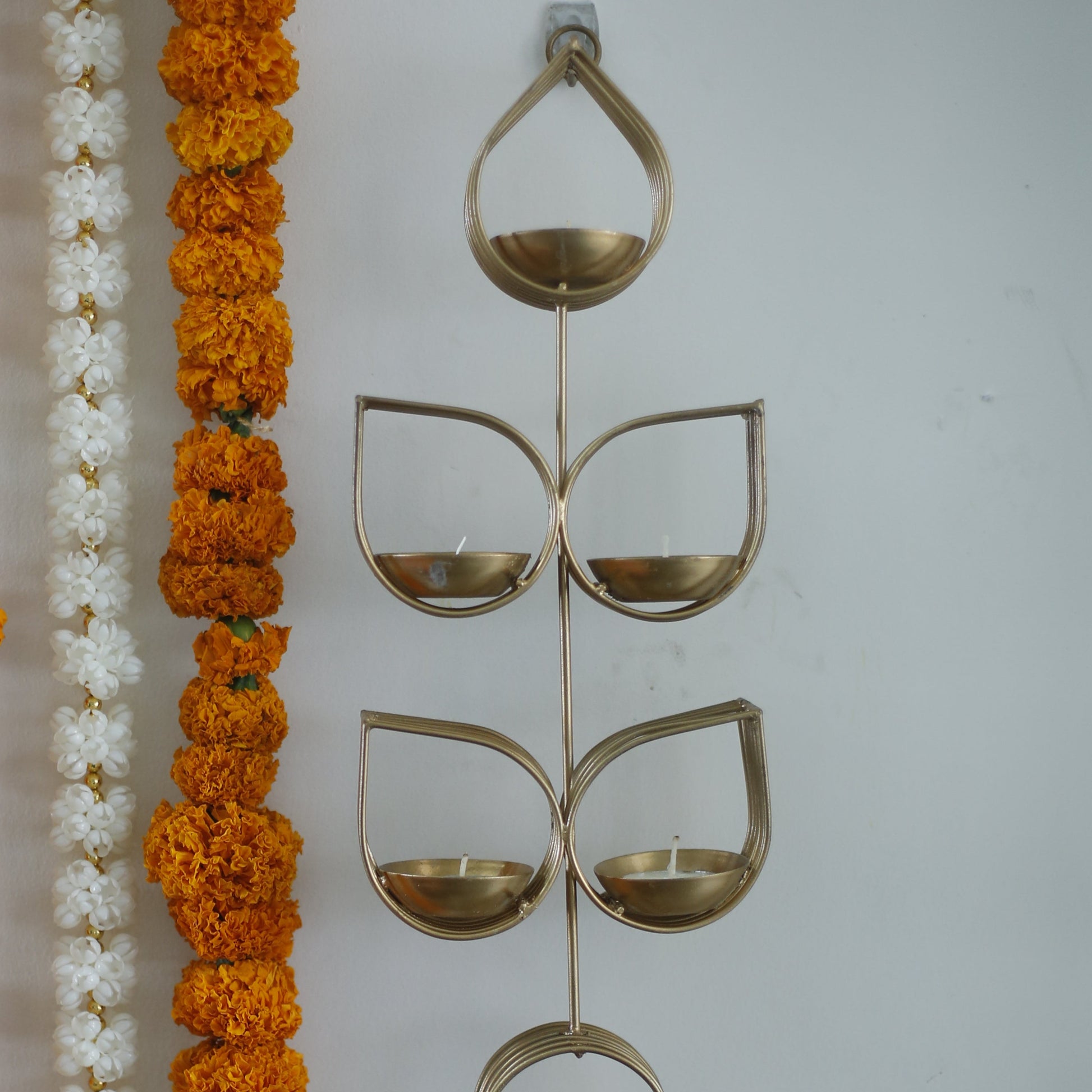 Decorative Tulsi tealight holder with orange and white flowers and a decorative metal piece on a white background