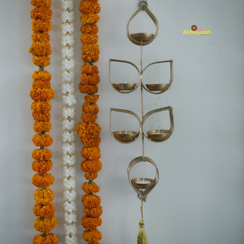 Decorative Tulsi tealight holder with orange and white flowers and a decorative metal piece on a gray background