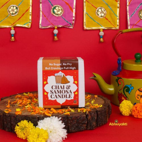 Decorative, usable soy candles shaped like a glass of chai with a biscuit and a triangular samosa, designed to look like popular Indian snacks