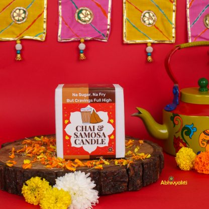 Decorative, usable soy candles shaped like a glass of chai with a biscuit and a triangular samosa, designed to look like popular Indian snacks