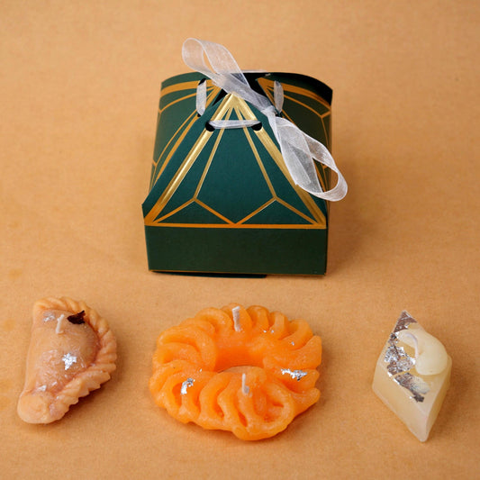 A beautifully designed candle box resembling a traditional Indian mithai (sweets) box. The box features bright, festive colors and intricate patterns, with multiple compartments holding candles shaped like popular Indian sweets such as ladoos, barfis, imarti and gujiya. Each candle has vibrant colors and detailed textures, evoking the look of real mithai, making it a perfect gift for festivals or special occasions.