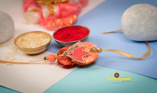 A decorative zari rakhi with a flower, stone, and delicate bead embellishments.