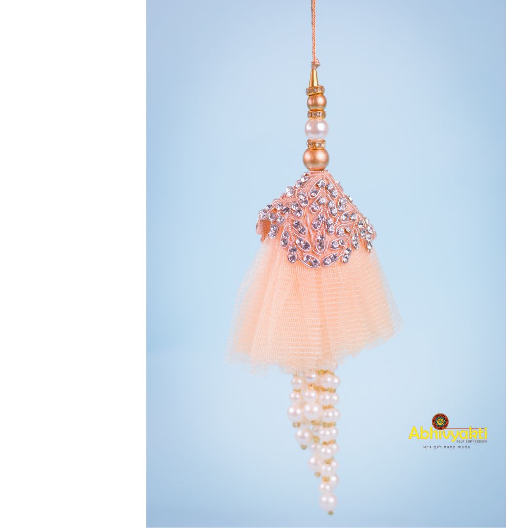 Rakhi lumba in pink and white colors, embellished with pearls and beads, boasting a unique design with beautiful stones.